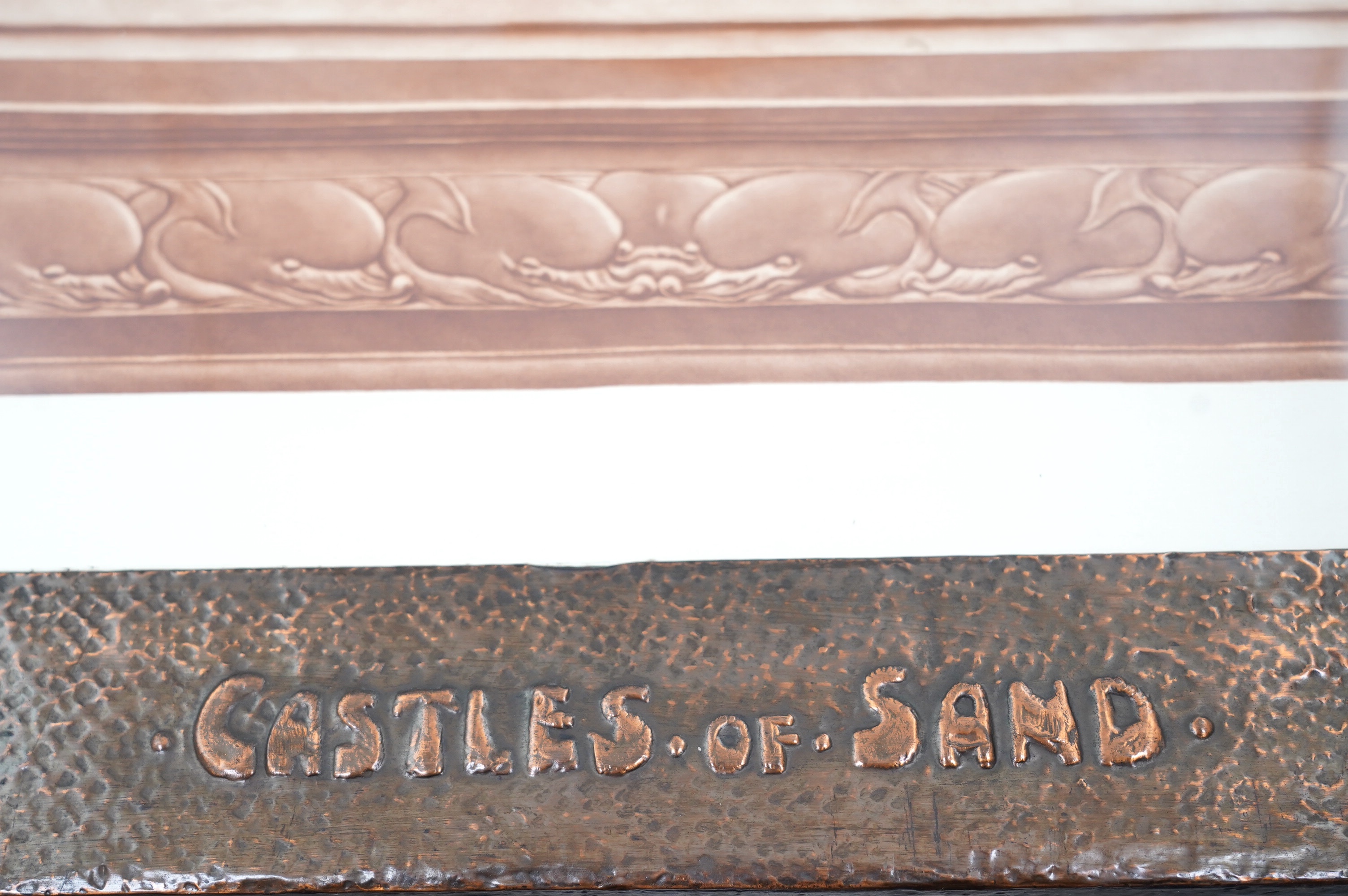 An Arts & Crafts large planished copper picture frame with fish motif to each corner, and with raised lettering 'Castles of Sand', inset with a mezzotint in sepia of Castles of Sand by William Henry Margetson (1861-1940)